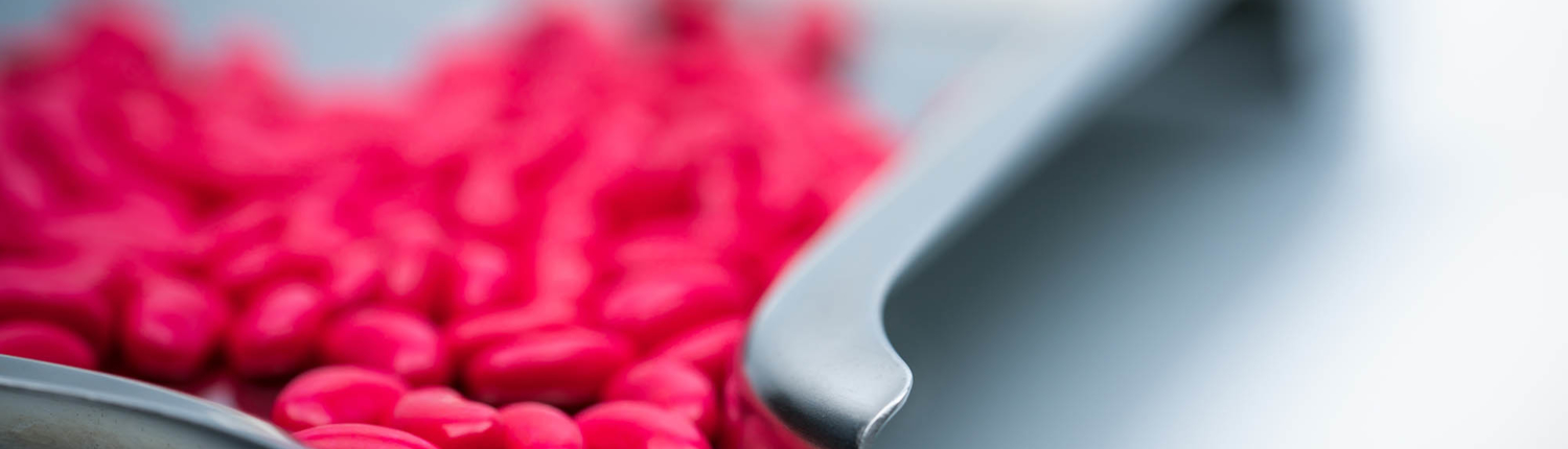 Coated red tablet on a metal chute Coated red tablet on a metal chute