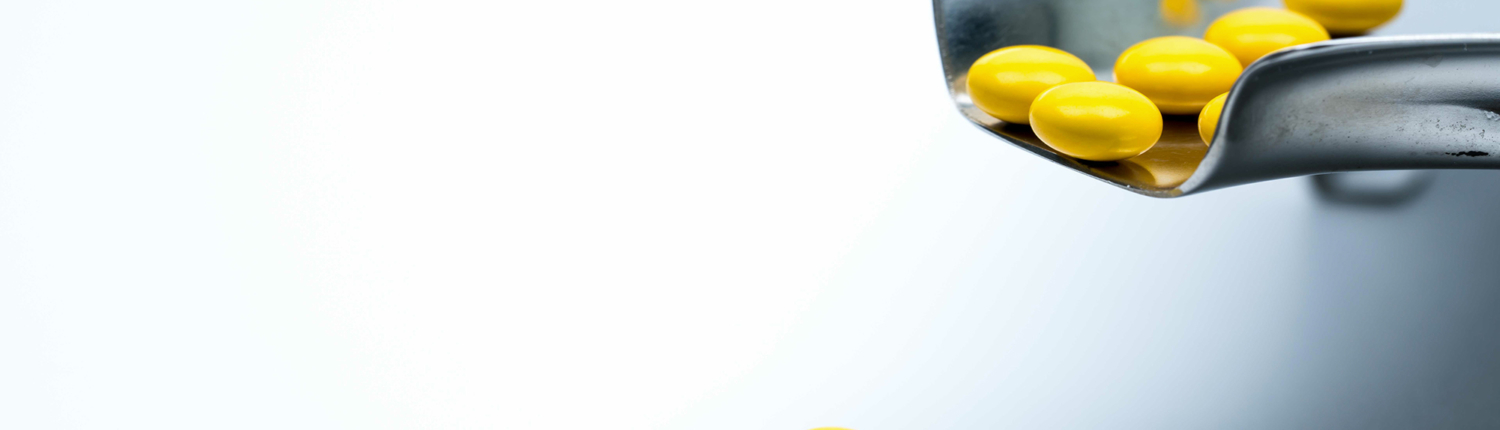 December Blog Image 2 View of yellow-coated tablets falling out out of a perforated coating pan